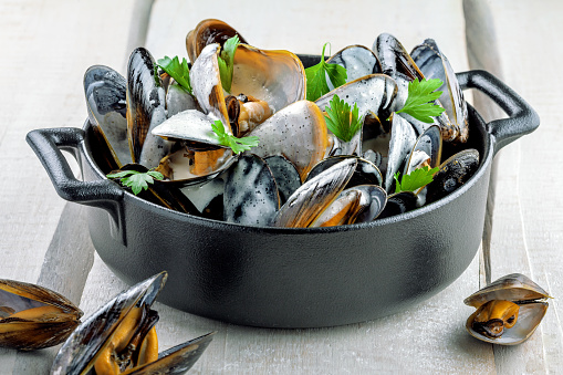 Delicious Steamed Mussels With Wine And Cream on a table. French meal Moules marinière in a bowl. Close-up shot.