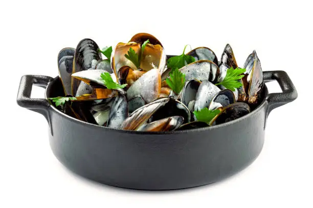 Mussels in a white wine and cream sauce on a table. Classic French meal Moules marinière isolated on white background.