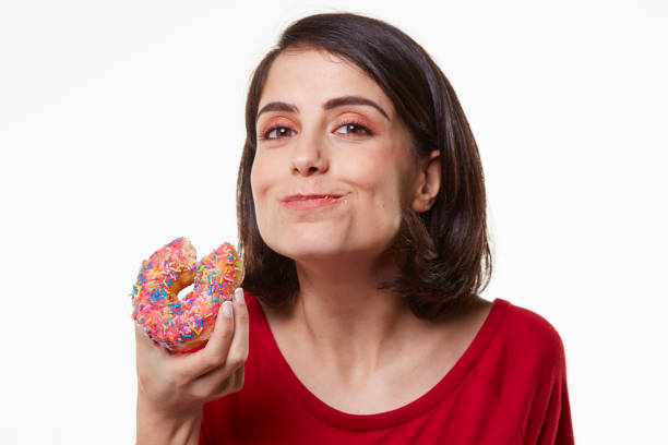 istock young woman eating a donut 965474790