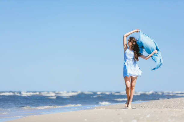 istock Young girl walking on the beach with blue scarf 965478186