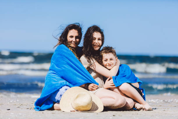 istock Mother, daughter and son sitting wrapped in a blanket. 965478192