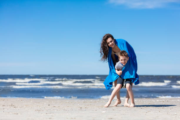 istock Older sister holding her little brother on the beach. 965478200