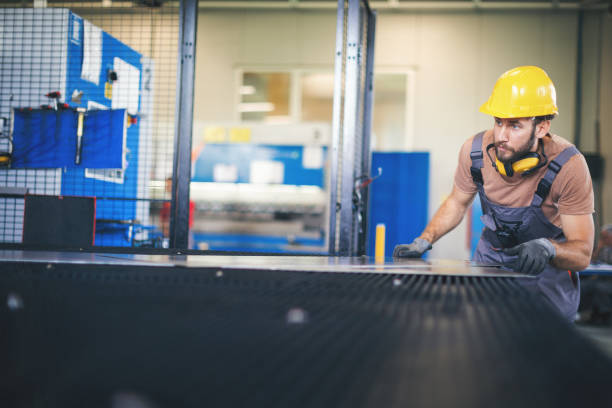 istock Young man processing metal plates in factory 965481164