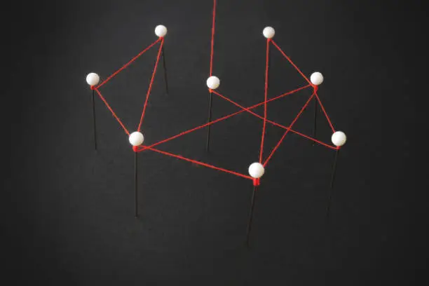 Photo of organizational structure or social network concept with pins and thread illustrating linkages and connections