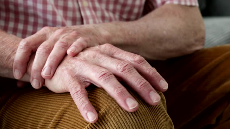 Close Up Of Man Suffering With Parkinsons Disease Holding Trembling Hand