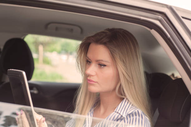 istock Woman sitting in car holding tablet. 965485112