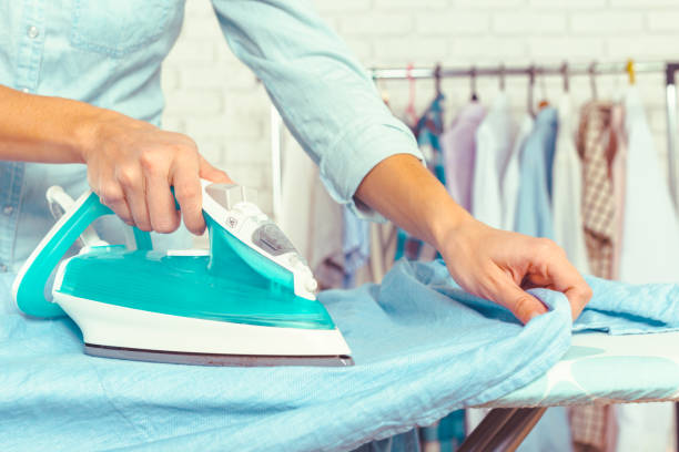 istock Closeup of woman ironing clothes on ironing board 965487724
