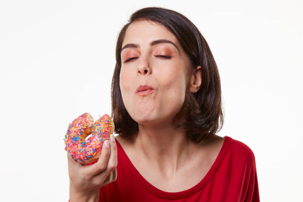 istock young woman eating a donut 965488578