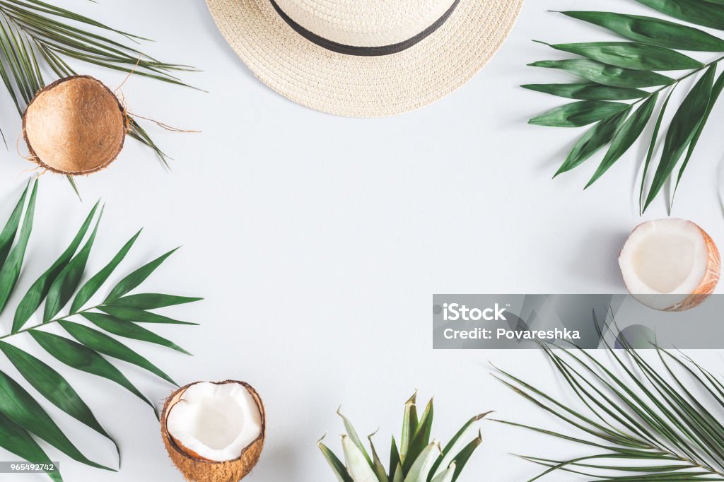 Tropical palm leaves, hat, coconut on pastel blue background Summer composition. Tropical palm leaves, hat, coconut on pastel blue background. Summer concept. Flat lay, top view, copy space Summer Stock Photo