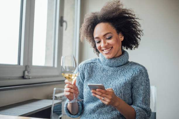 mujer feliz con teléfono inteligente y disfrutar de un vino - glass drink alcohol red fotografías e imágenes de stock