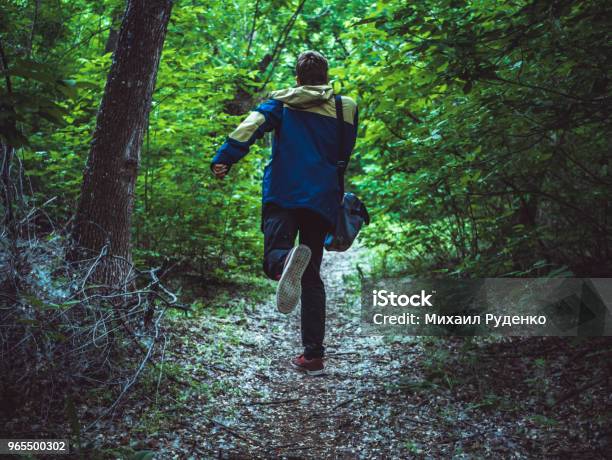 Young Scary Man Running Away In The Dark Forest On The Path Back View Stock Photo - Download Image Now