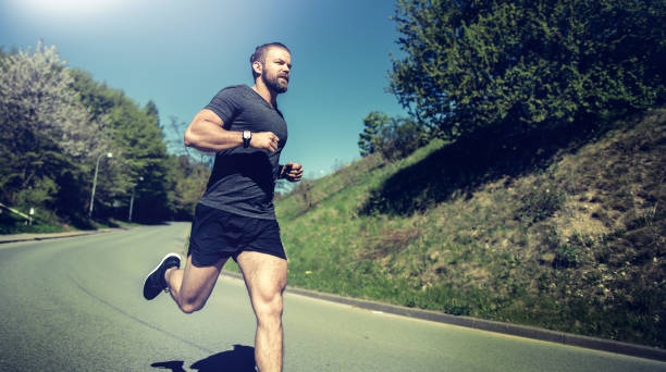 fit young man running alone down a country road - nordic running imagens e fotografias de stock