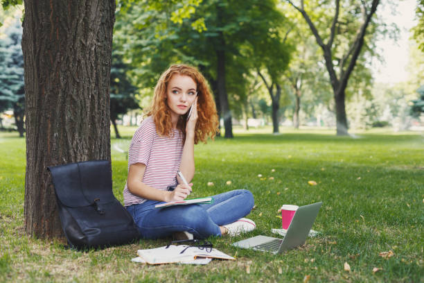 istock Happy young woman talking on smartphone in park 965503762