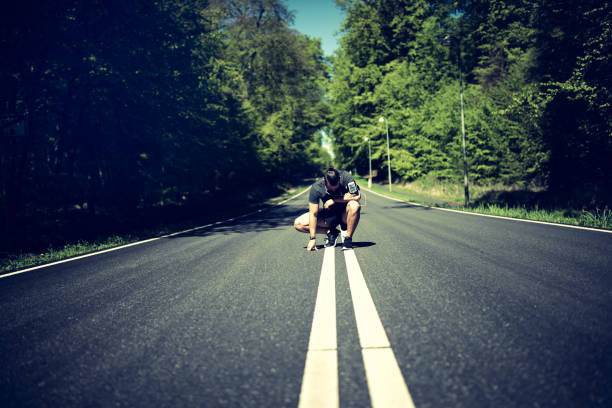 istock Man kneeling on a country road looking exhausted after jogging 965504054