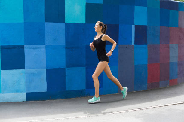 istock Side view of woman running against bright wall 965504434