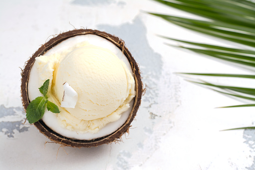 Coconut ice cream scoops in halves of coconut shell on white background. Copy space
