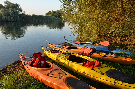 Colorful loaded kayaks stand on river bank parked for night. Danube Delta, Romania.