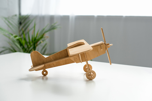 close up view of wooden toy plane on white tabletop
