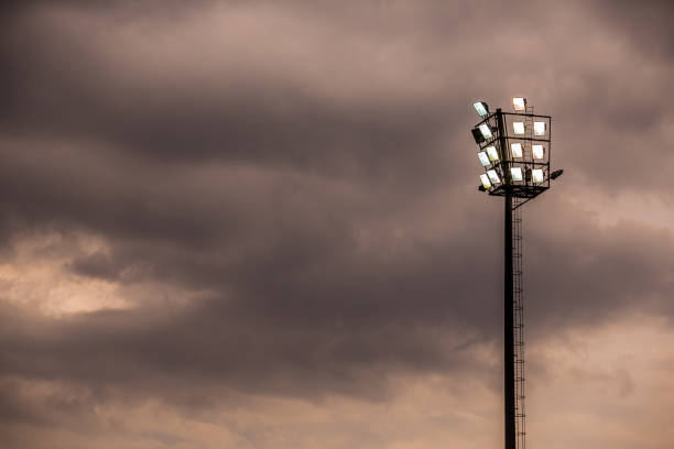 estádio de esportes brilhantes luzes em uma noite nublada - floodlight blue sky day - fotografias e filmes do acervo