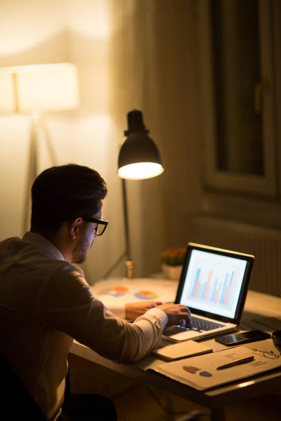 istock Man working with laptop late at night at home 965522600