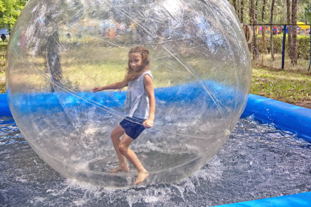 Attraction on the water - zorbing Zorbing in park. The girl runs inside a transparent sphere zorb ball stock pictures, royalty-free photos & images