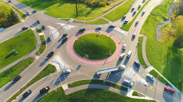 Busy city roundabout intersection at sunrise rush hour, aerial view.