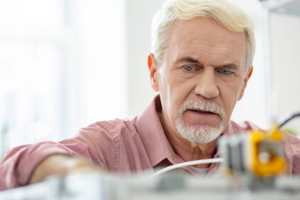 istock Close up of charming senior man working with 3D printer 965531618
