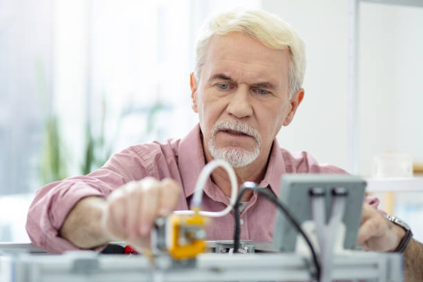 istock Pleasant senior man changing settings of 3D printer 965532118