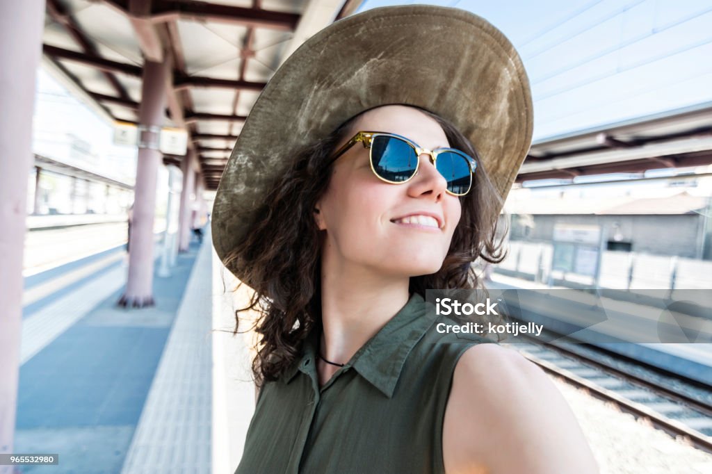 Pretty young woman in a train station Smiling young woman in a train station looking over shoulder Adult Stock Photo