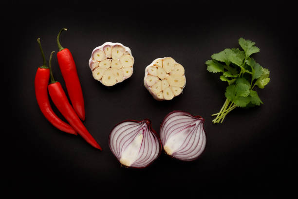 Initial ingredients, for tasty, spicy food with chilli, garlic, coriander and onion, shot on a dark slate background. Initial ingredients, for tasty, spicy food with chilli, garlic, coriander and onion, shot on a dark slate background. fresh cilantro stock pictures, royalty-free photos & images