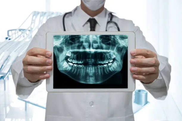 Dentist holding a digital tablet with x-ray of teeth in a clinic dental office