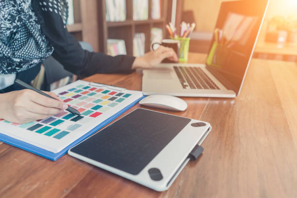 istock Young creative designer working with color palette samples and pen tablets for selection on office desk.Designer workplace. 965534196