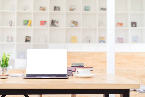 istock Blank screen laptop mockup on wood table in co-working space and blurred bookshelf background.Blank screen laptop for graphic display montage. 965536836