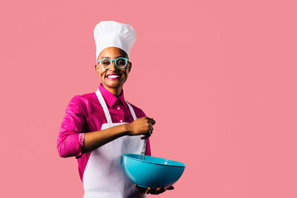 Portrait of a young woman with hat and glasses Portrait of a young woman, isolated on pink studio background apron photos stock pictures, royalty-free photos & images