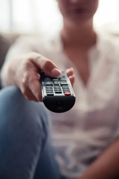 Front view of a woman holding a remote control.