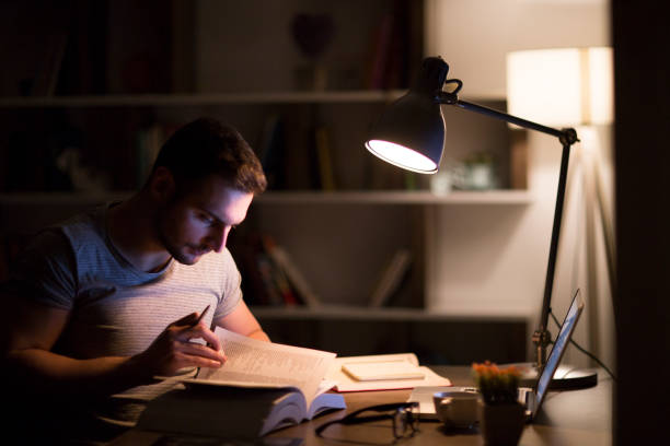 istock Student studying at night with a desk lamp on 965556938