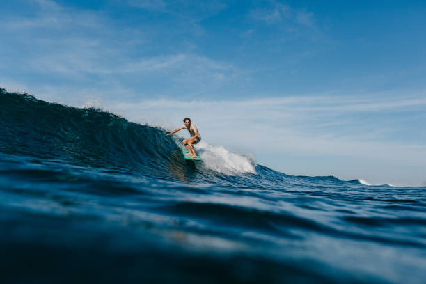 istock handsome man in wet t-shirt riding waves on surfboard 965557658