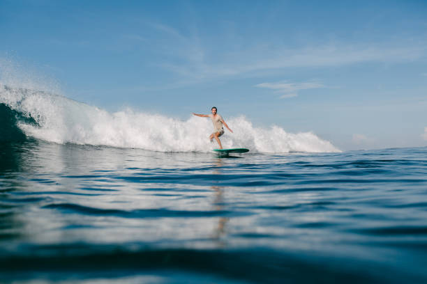 istock handsome sportsman riding waves on surfboard on sunny day 965560138