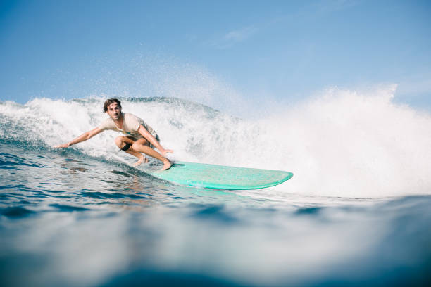 istock handsome man in wet t-shirt riding waves on surfboard while having vacation 965560210