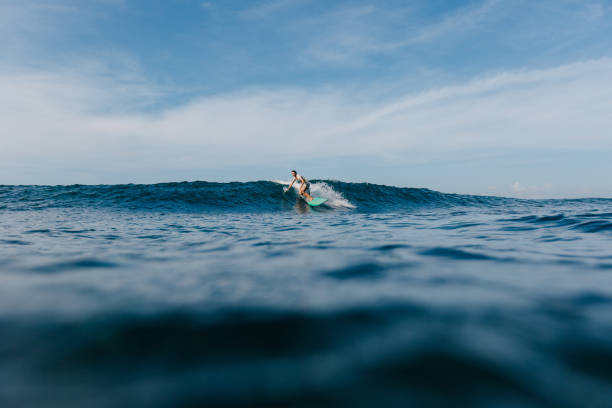 istock handsome man riding blue ocean waves on surfboard 965560262