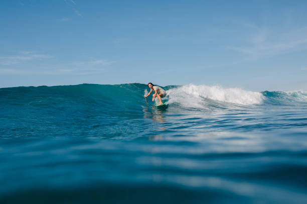 istock young man in wet t-shirt riding blue waves on surfboard while having vacation 965560820