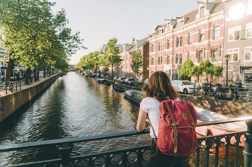 Young Caucasian woman  walking near canal in Amsterdam at sunset