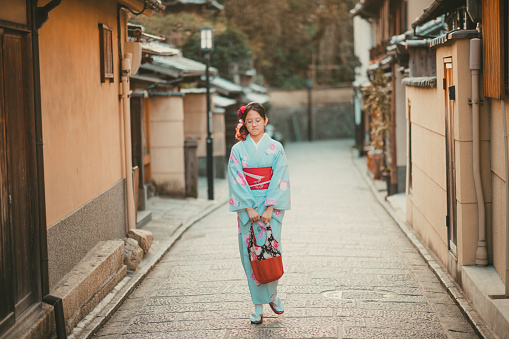 asian chinese teenager girl wearing japanese tradition kimono and walking in the alley of kyoto