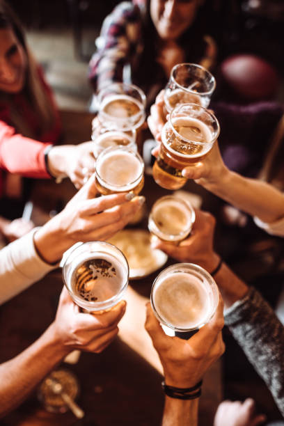 people talking toasting in a pub with the beers people talking toasting in a pub with the beers cheers beer stock pictures, royalty-free photos & images