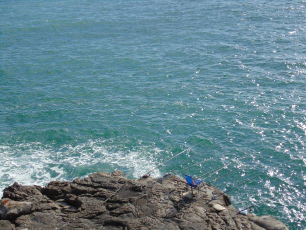 istock Fishing rod and fisherman empty chairs in a rock formation. 965591780