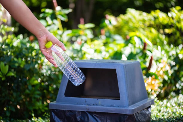 istock World Environment Day, June 5. Woman hand holding and putting plastic bottle waste into garbage trash. 965601886