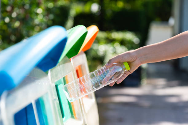 istock World Environment Day, June 5. Woman hand holding and putting plastic bottle waste into garbage trash. 965601936