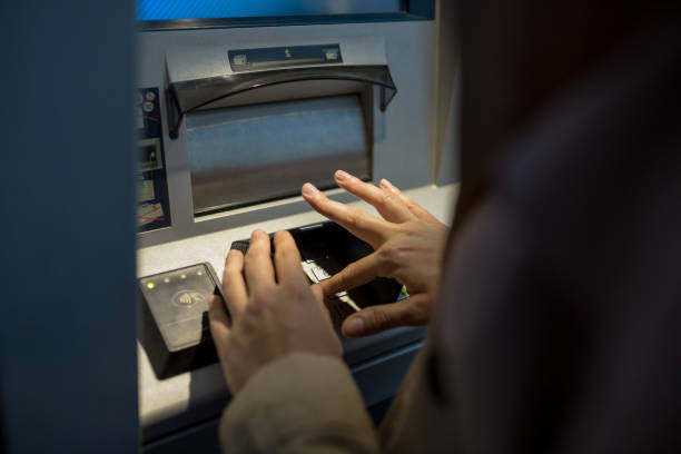 istock young woman inserting a credit card to ATM 965602466