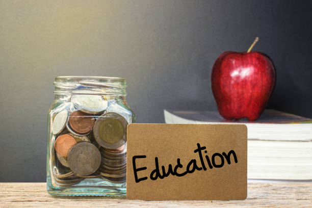 istock Conceptual saving money for education with blurred red apple on books with light as background. 965644636