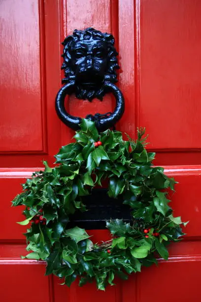 flower wreath decoration on red door with black lion doorknob for christmas